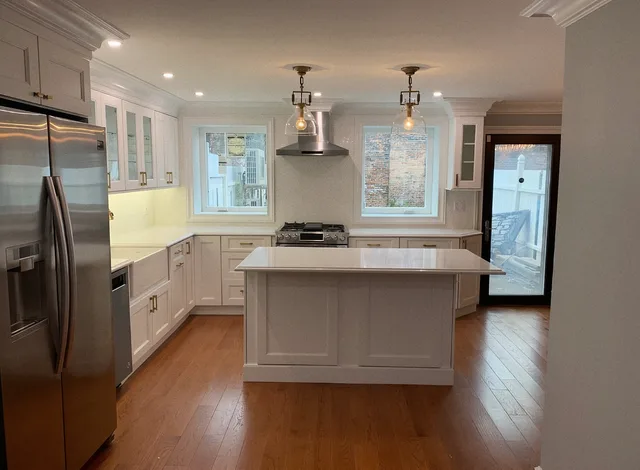 Finished white kitchen with an island, glass pendants and hardwood floors